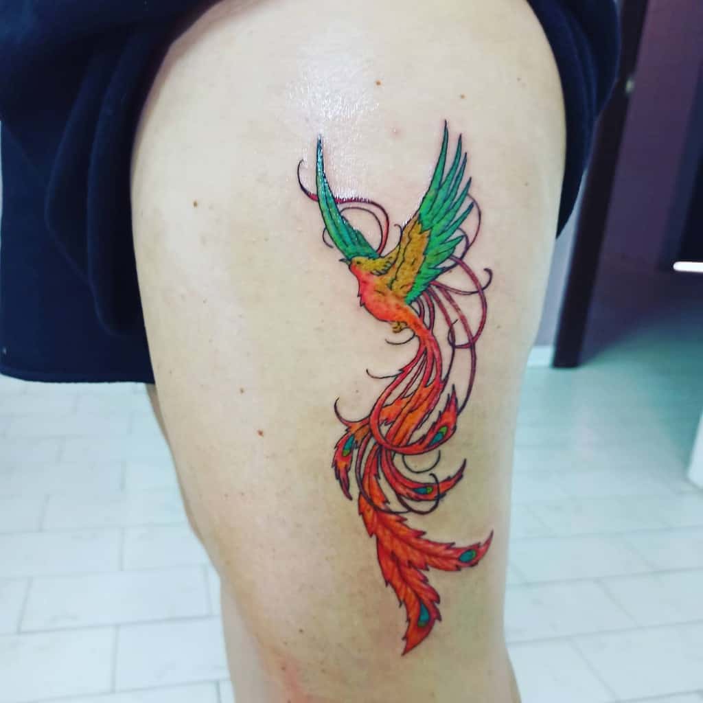 A colorful phoenix rising tattoo graces a person's upper thigh