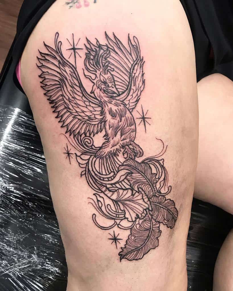 Tattoo of a phoenix rising, brilliantly inked on a person's thigh, with stars twinkling in the background