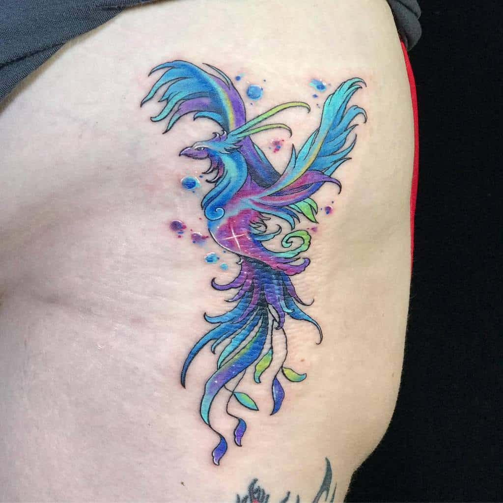 Colorful phoenix rising tattoo with blue, green, and purple hues on a hip