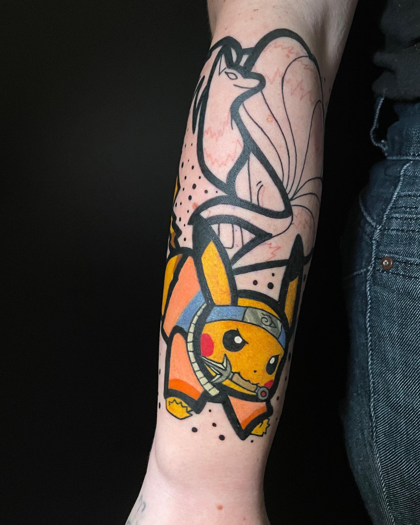 Tattoo of Pikachu on a forearm wearing a ninja headband with a flower above