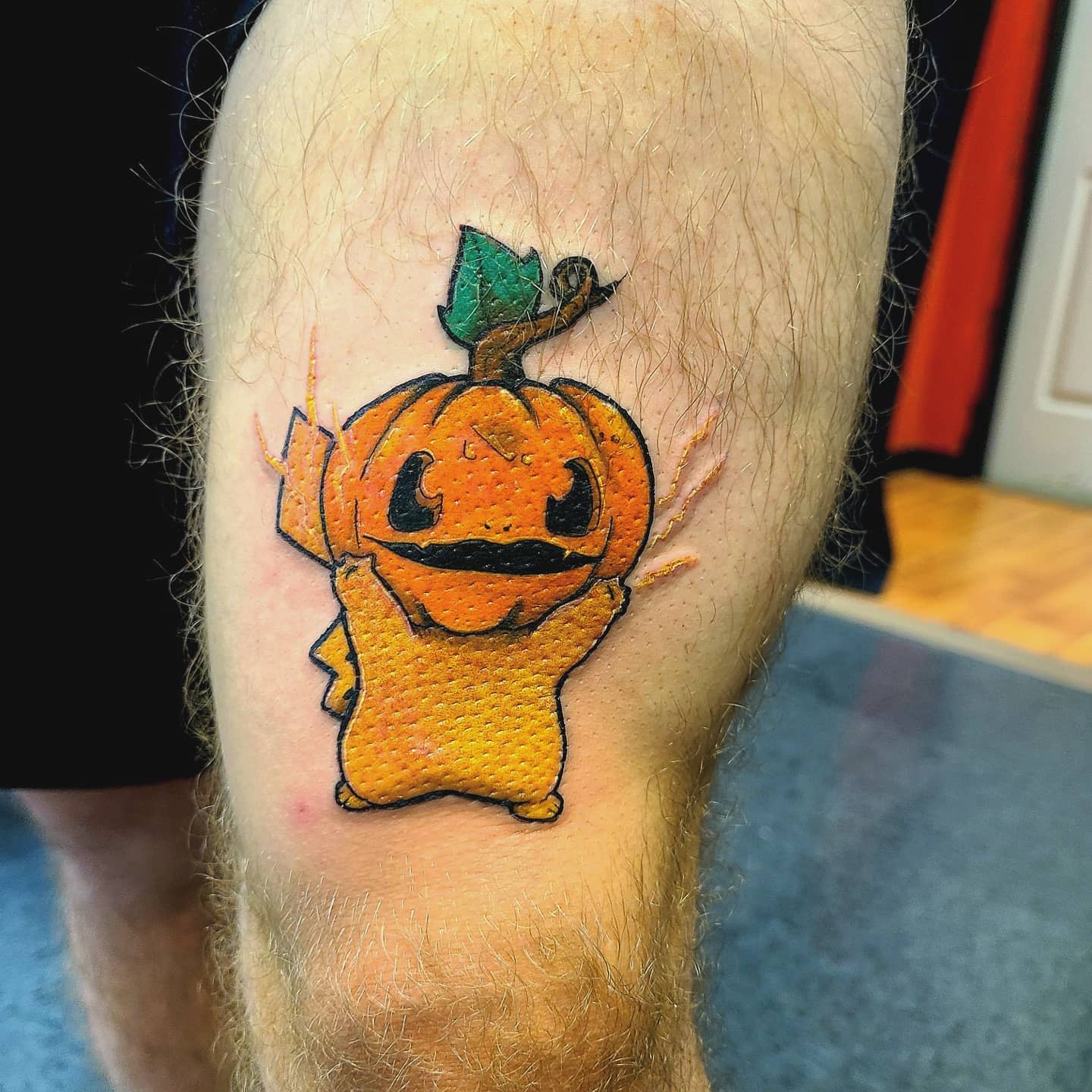 Tattoo of Pikachu with a pumpkin head on a leg