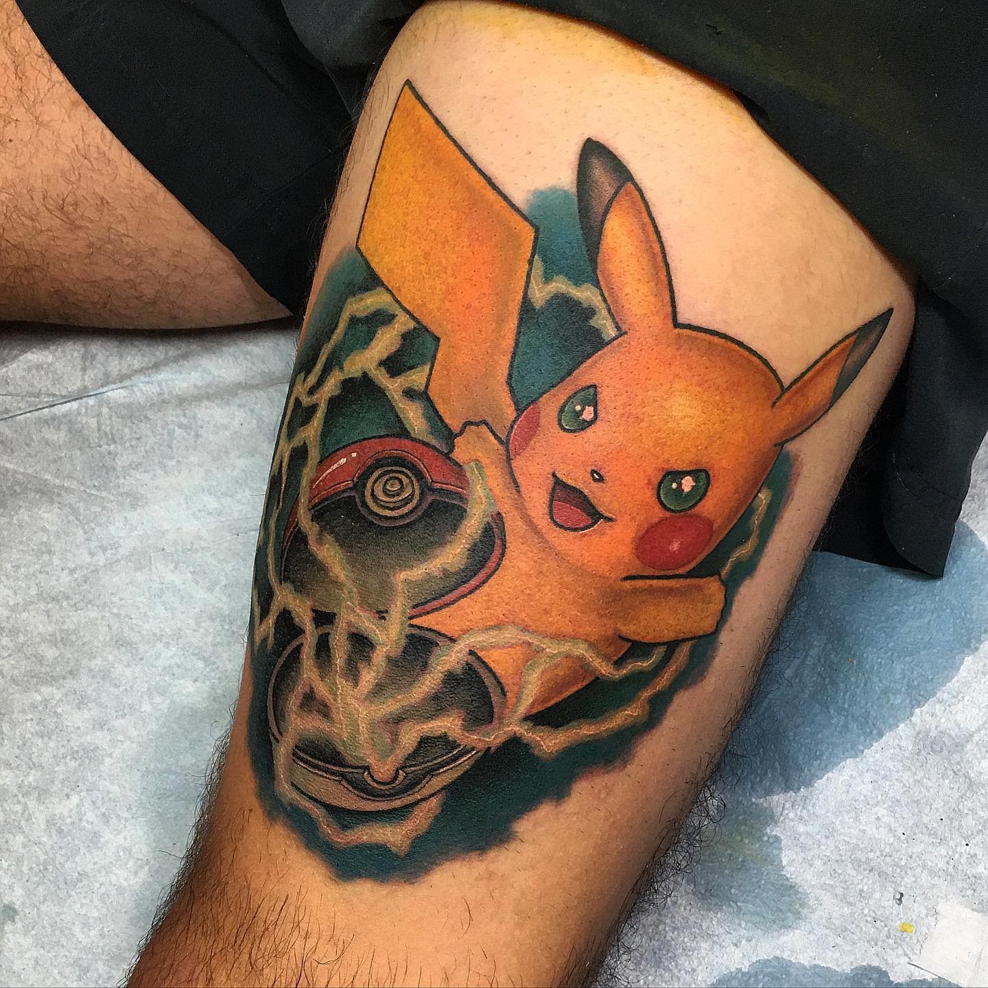 Tattoo of Pikachu holding a Poké Ball on a thigh