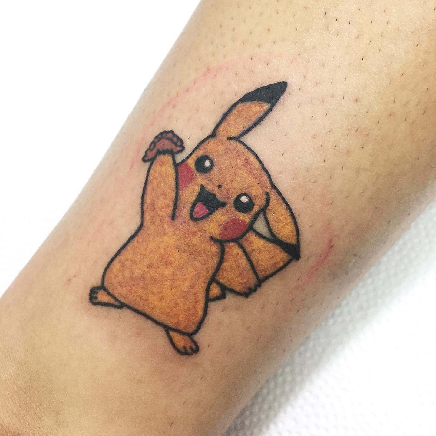 A small tattoo of Pikachu on an arm