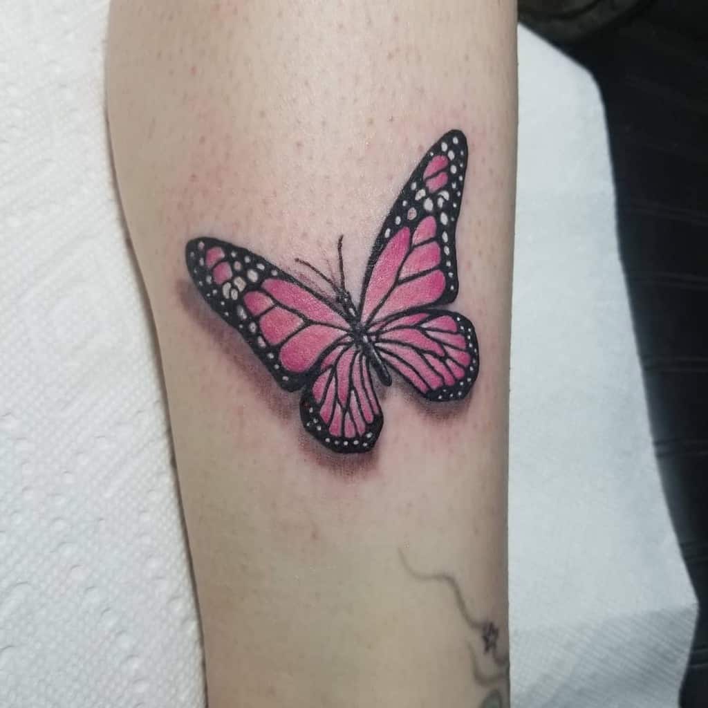 Pink butterfly tattoo with black outlines and white spots