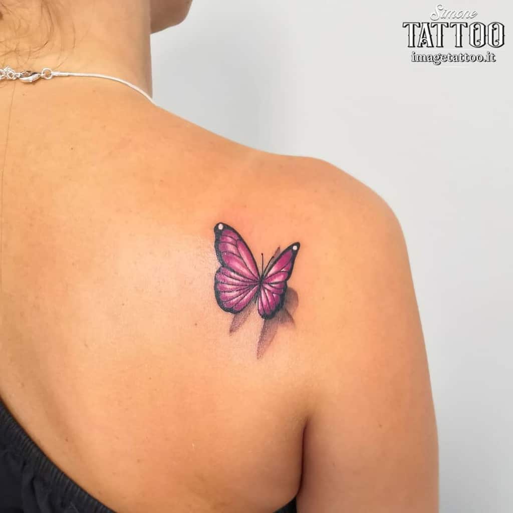 A pink butterfly tattoo on a woman's upper back near her shoulder