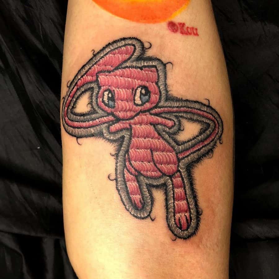 Tattoo of Mew floating playfully, designed with detailed embroidery shading and a thread-like stitched outline.