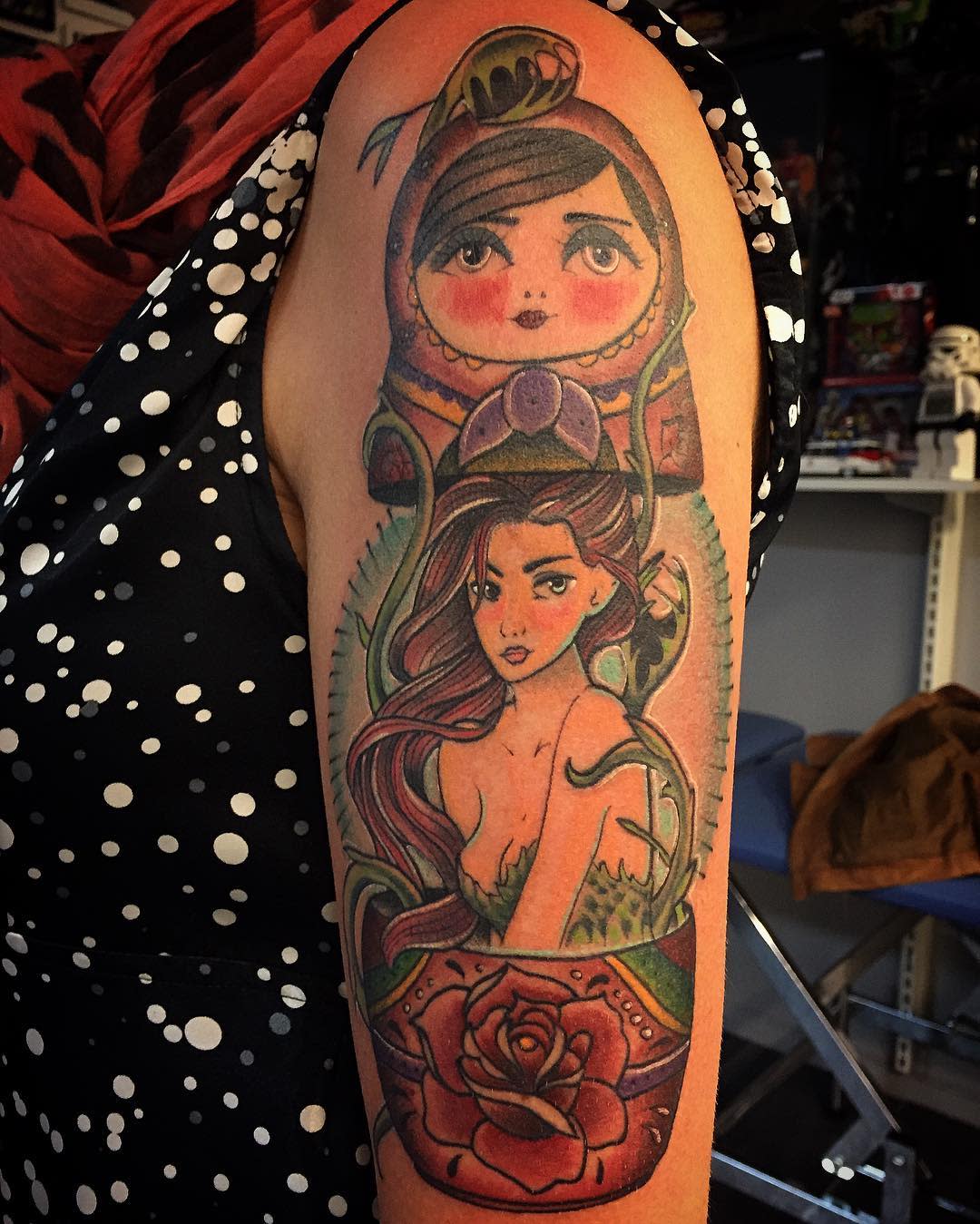 Upper arm tattoo of stacked matryoshka dolls with a rose