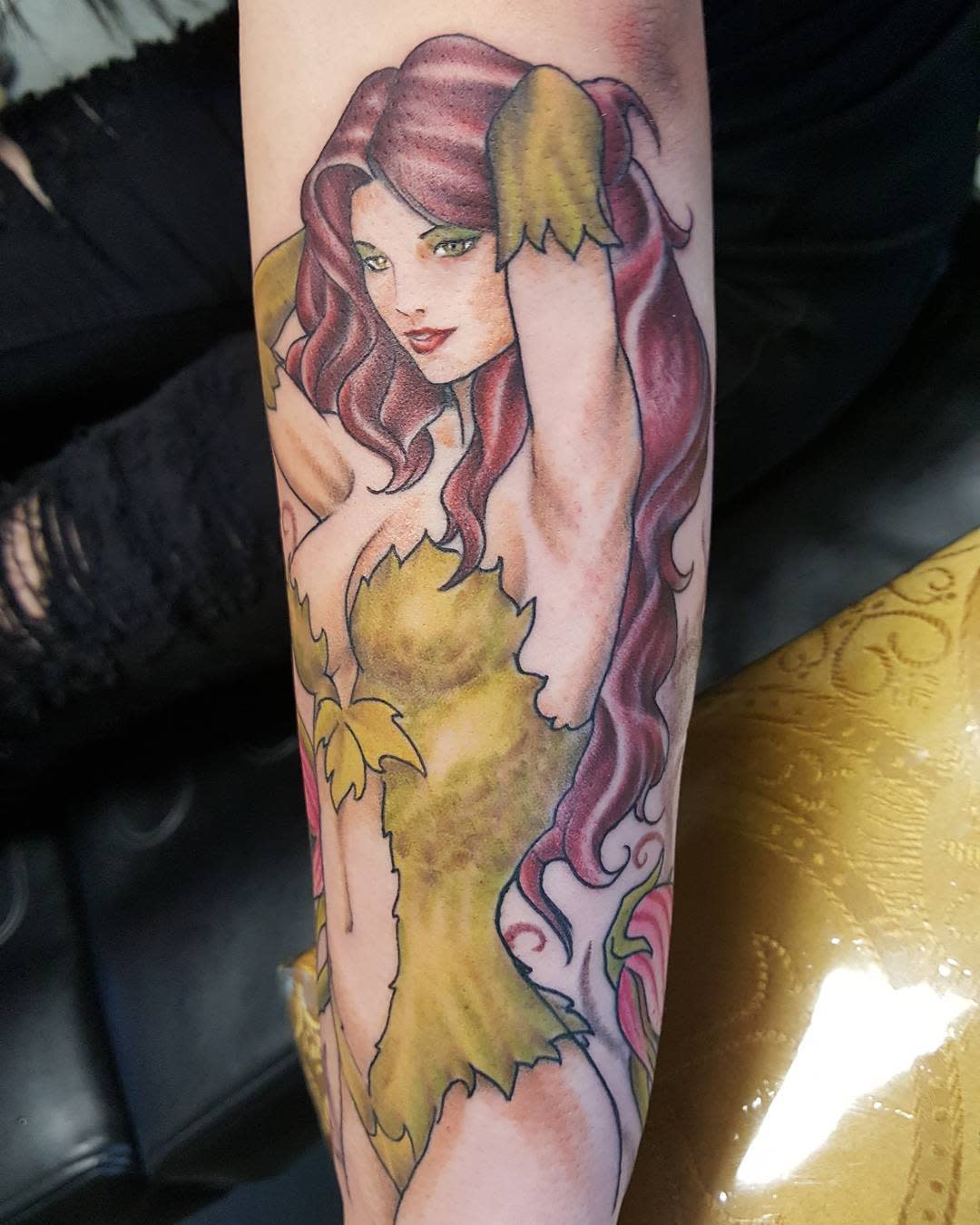 Forearm tattoo of a woman covered in a poison ivy with flowing red hair