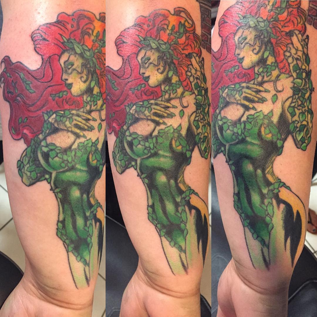 Colorful tattoo of a woman with red hair and poison ivy attire covering a forearm
