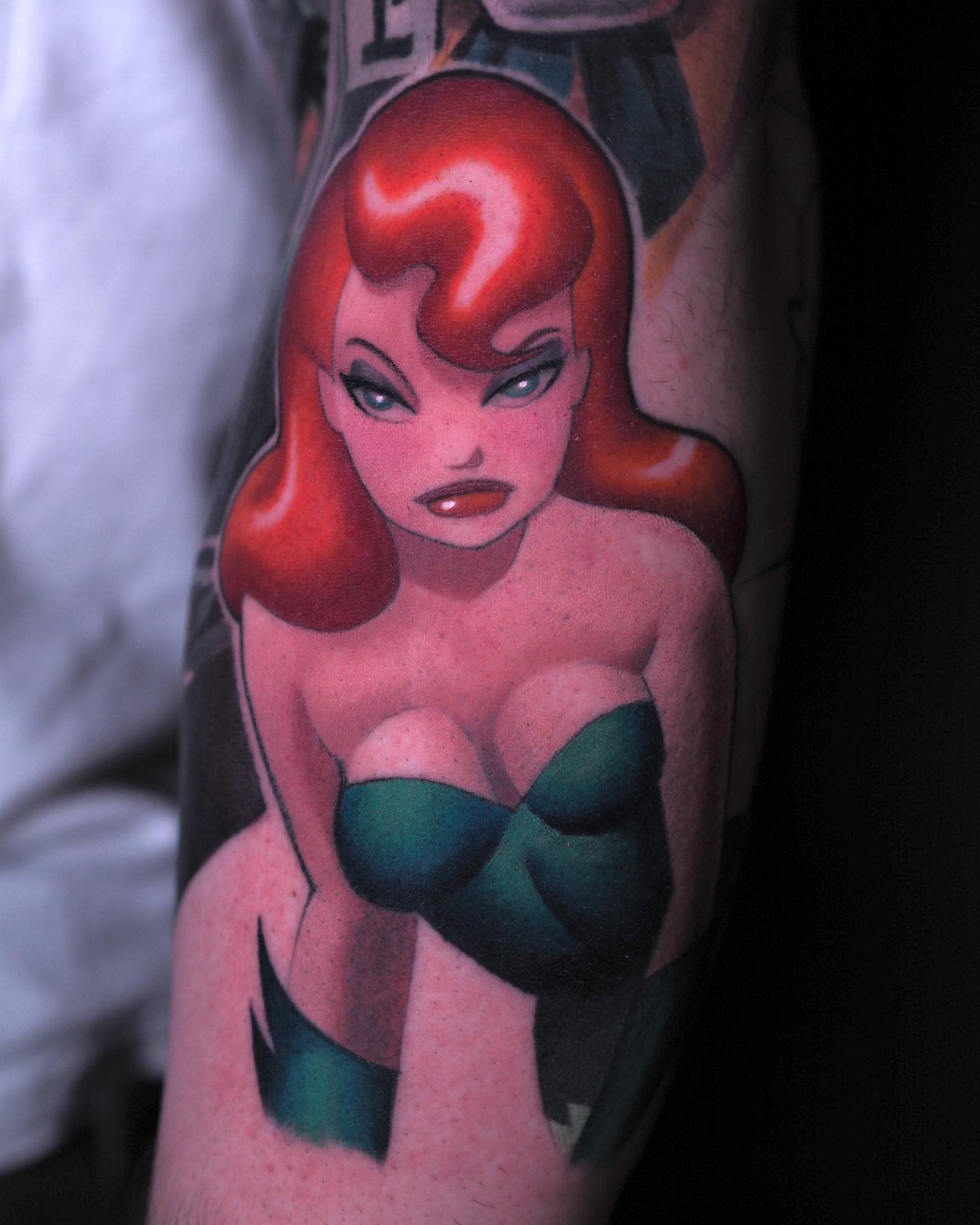 Tattoo of a red-haired woman in a green outfit on an arm