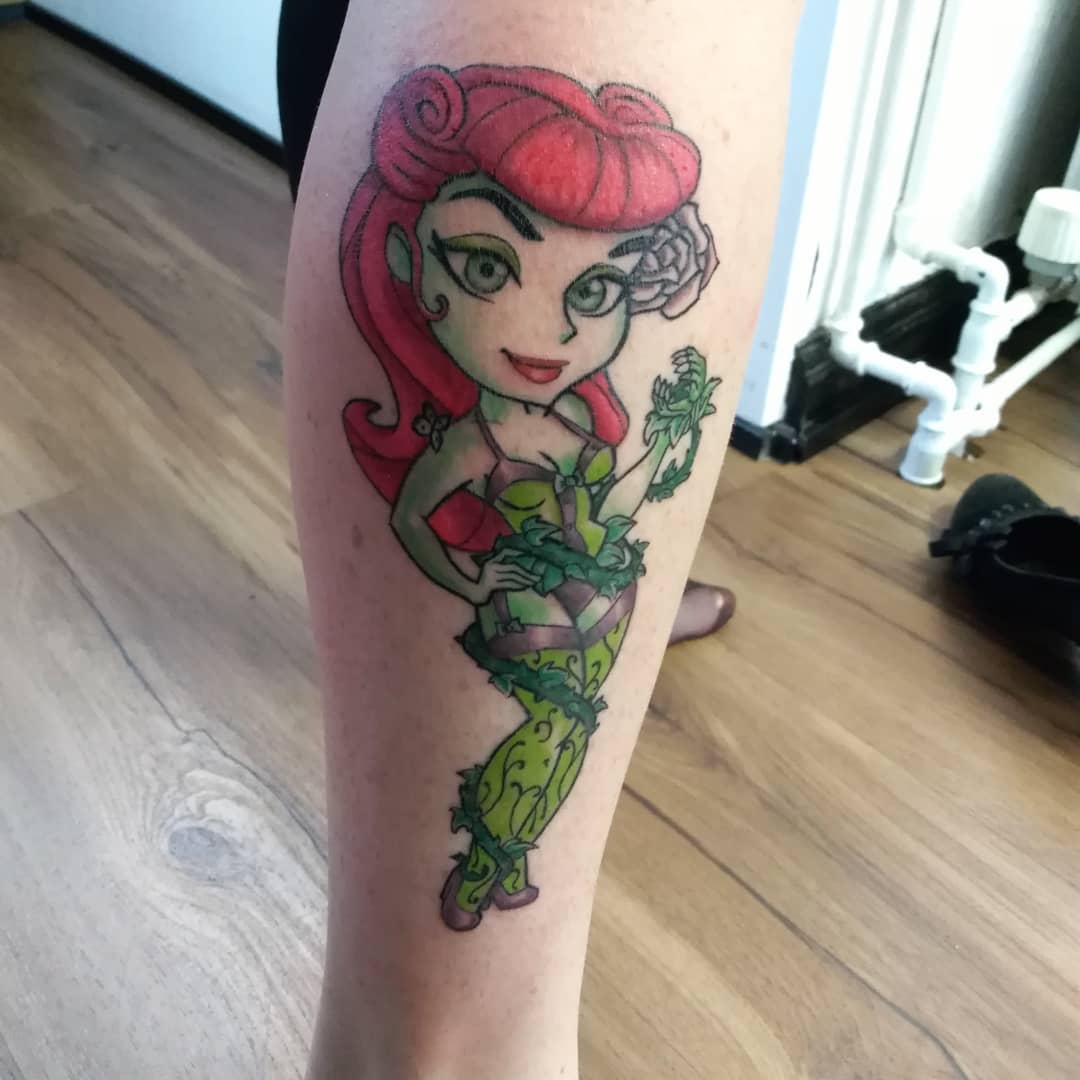 Tattoo of a woman with red hair and green outfit on the back of a calf