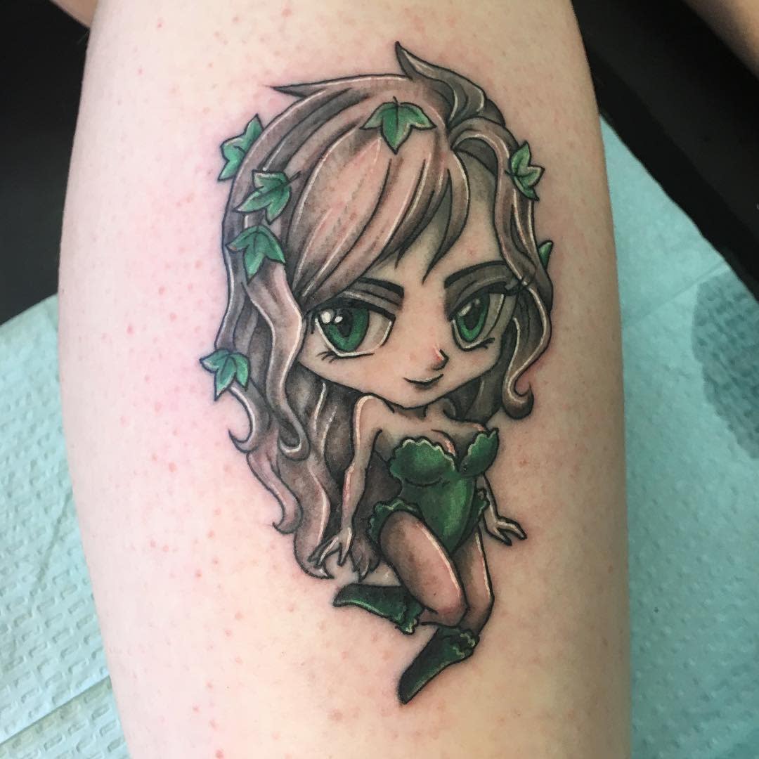 Tattoo of a cartoon woman with green eyes, leaves in hair, and green outfit