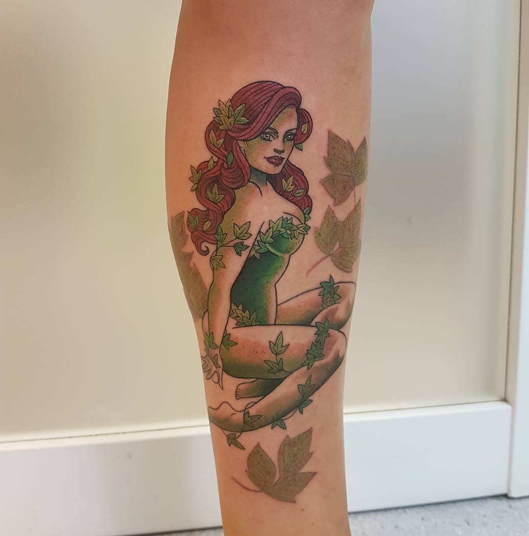Tattoo of a woman with red hair and green poison ivy leaves on a calf