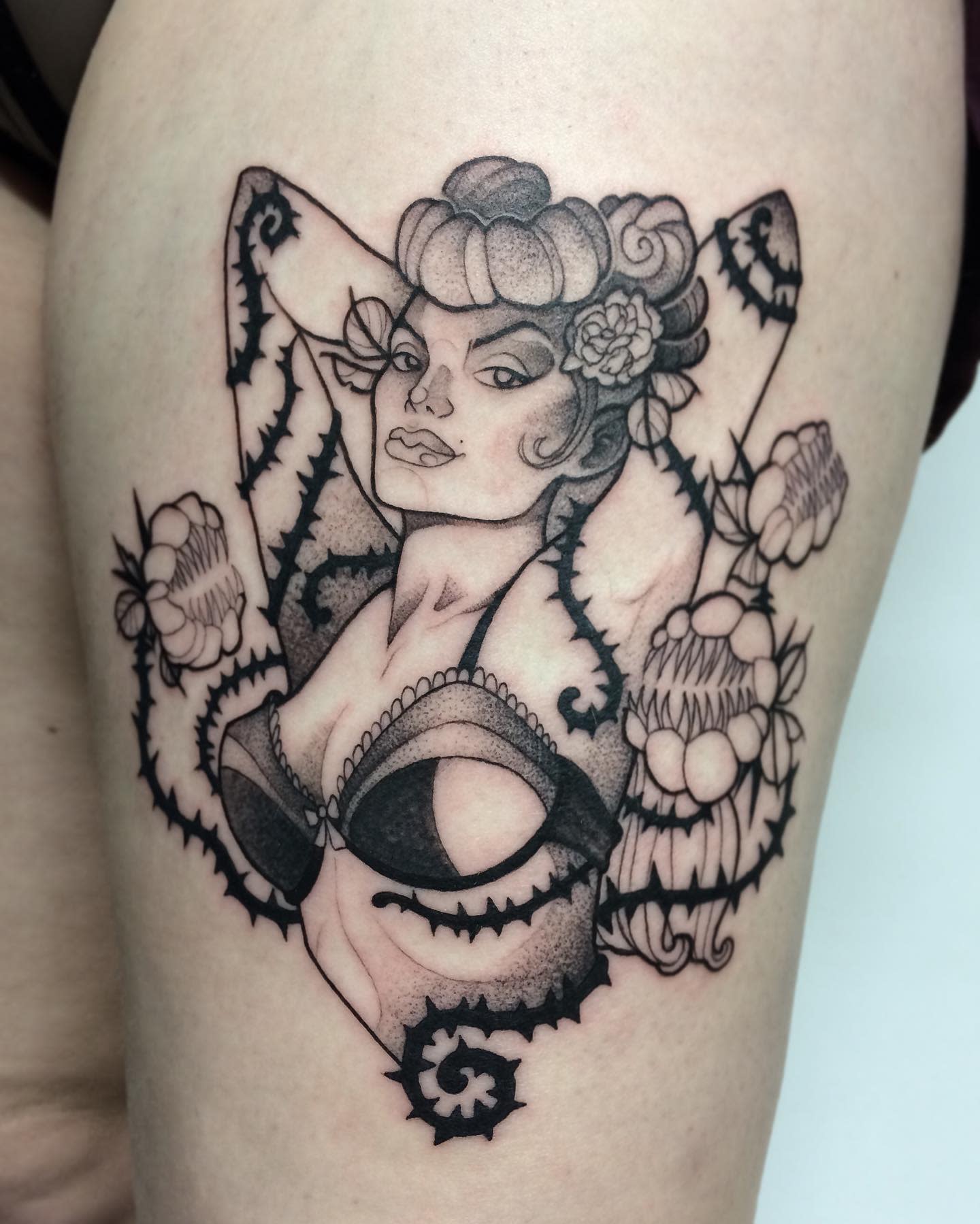 Tattoo of a woman in lingerie with floral and leaf designs on the upper thigh