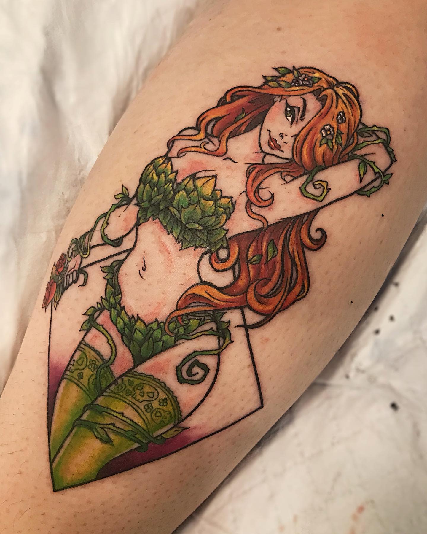 Tattoo of a woman with long hair and poison ivy leaf outfit on an arm