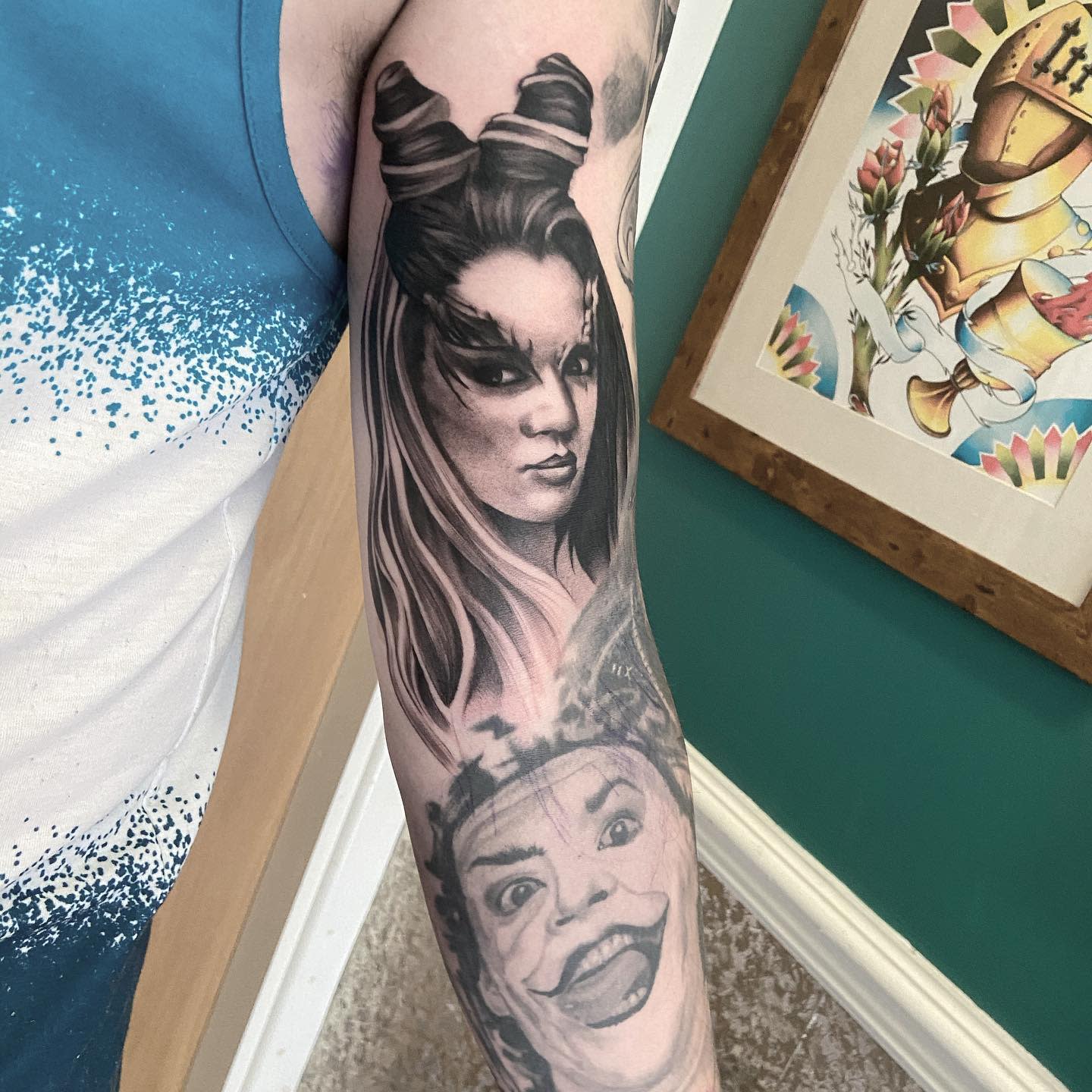 Arm tattoo featuring two detailed faces: a serene woman and another with a wide grin