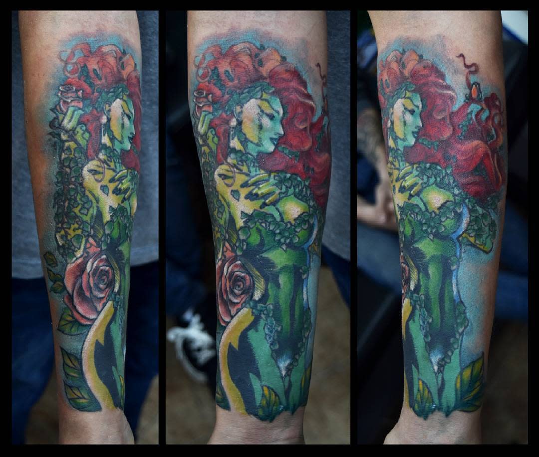 Forearm tattoo of a woman with red hair surrounded by plants and flowers