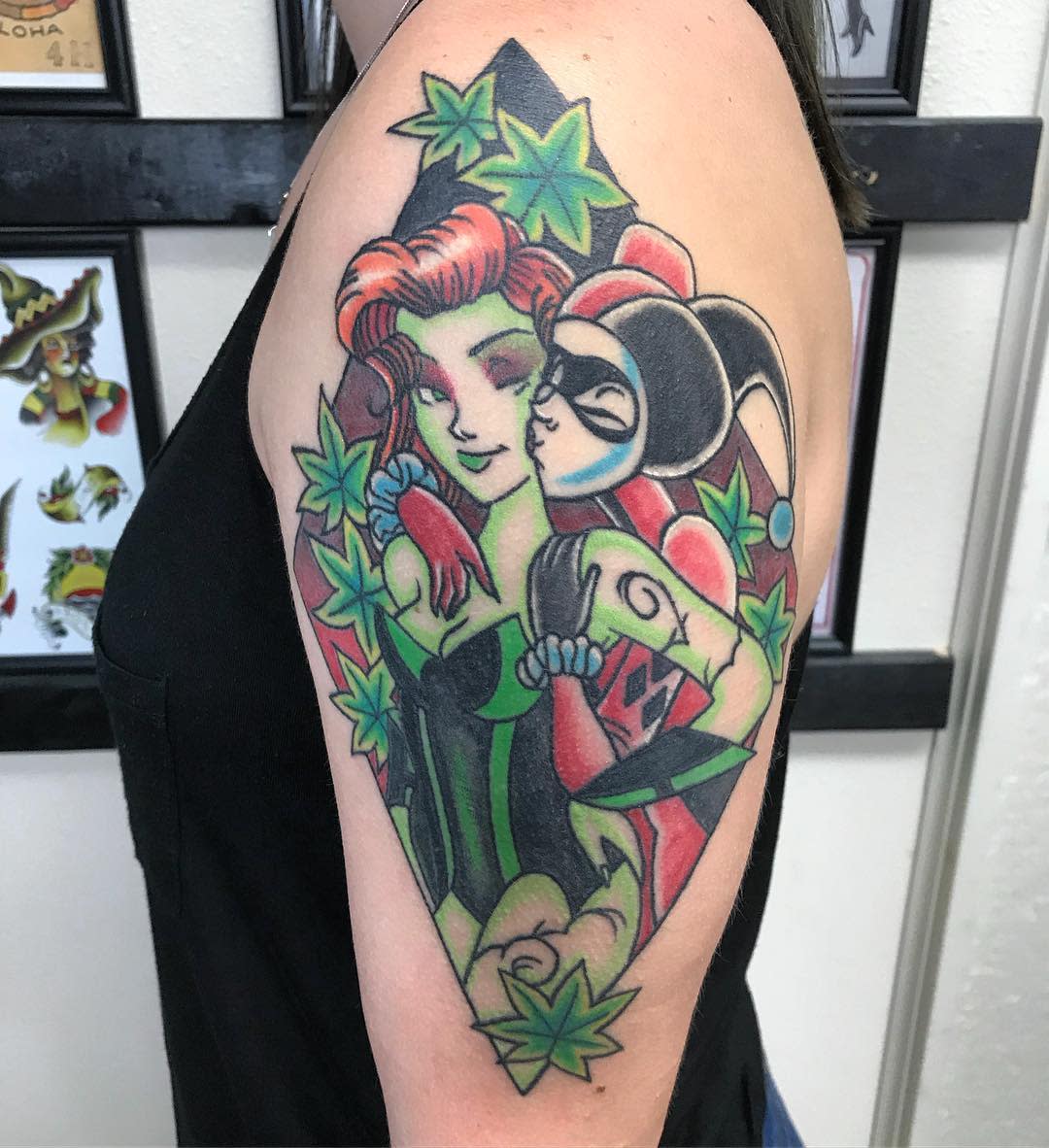 Colorful tattoo of two comic characters with green poison ivy leaves on an upper arm