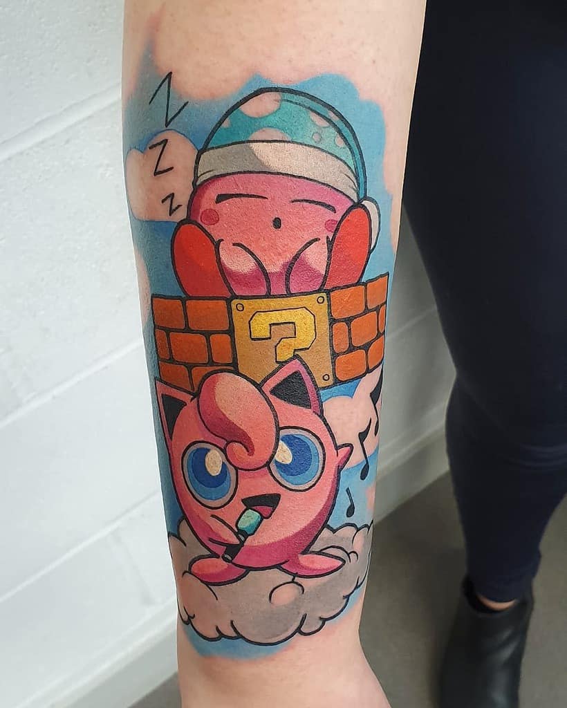 Kirby tattoo sleeping with "ZZZ" on a Super Mario question block while Jigglypuff sings on a cloud below with blue background