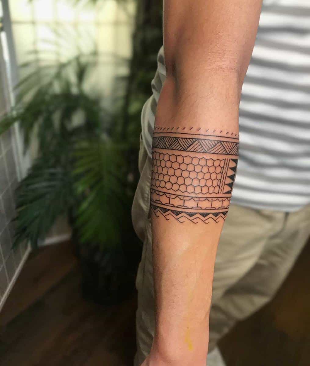 Forearm with an intricate geometric tattoo design featuring hexagons, zigzags, triangles, and a touch of Polynesian artistry