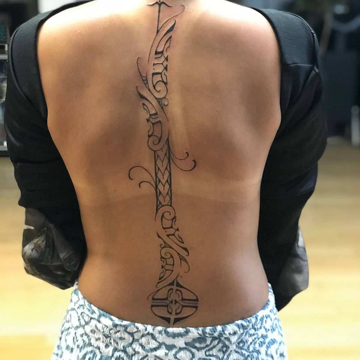 A detailed, vertically aligned Polynesian tattoo design covering the length of someone's back