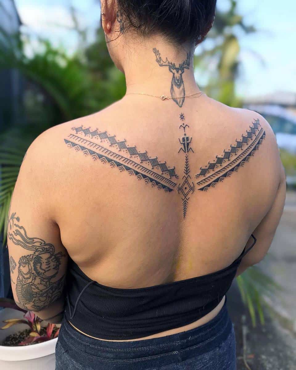 Intricate Polynesian geometric tattoos on back and neck, standing outdoors with plants nearby