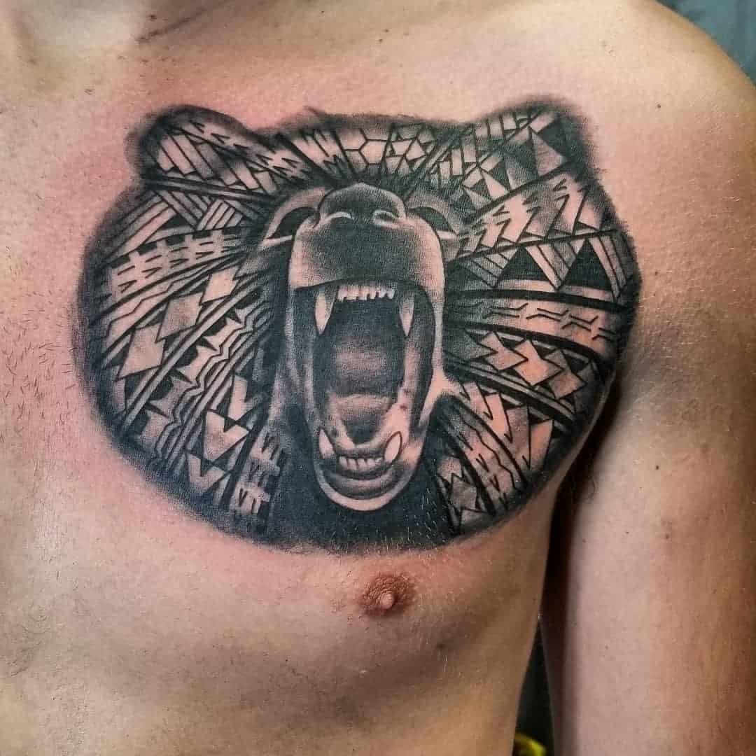 Chest tattoo of a roaring bear with intricate Polynesian tribal designs on the upper body