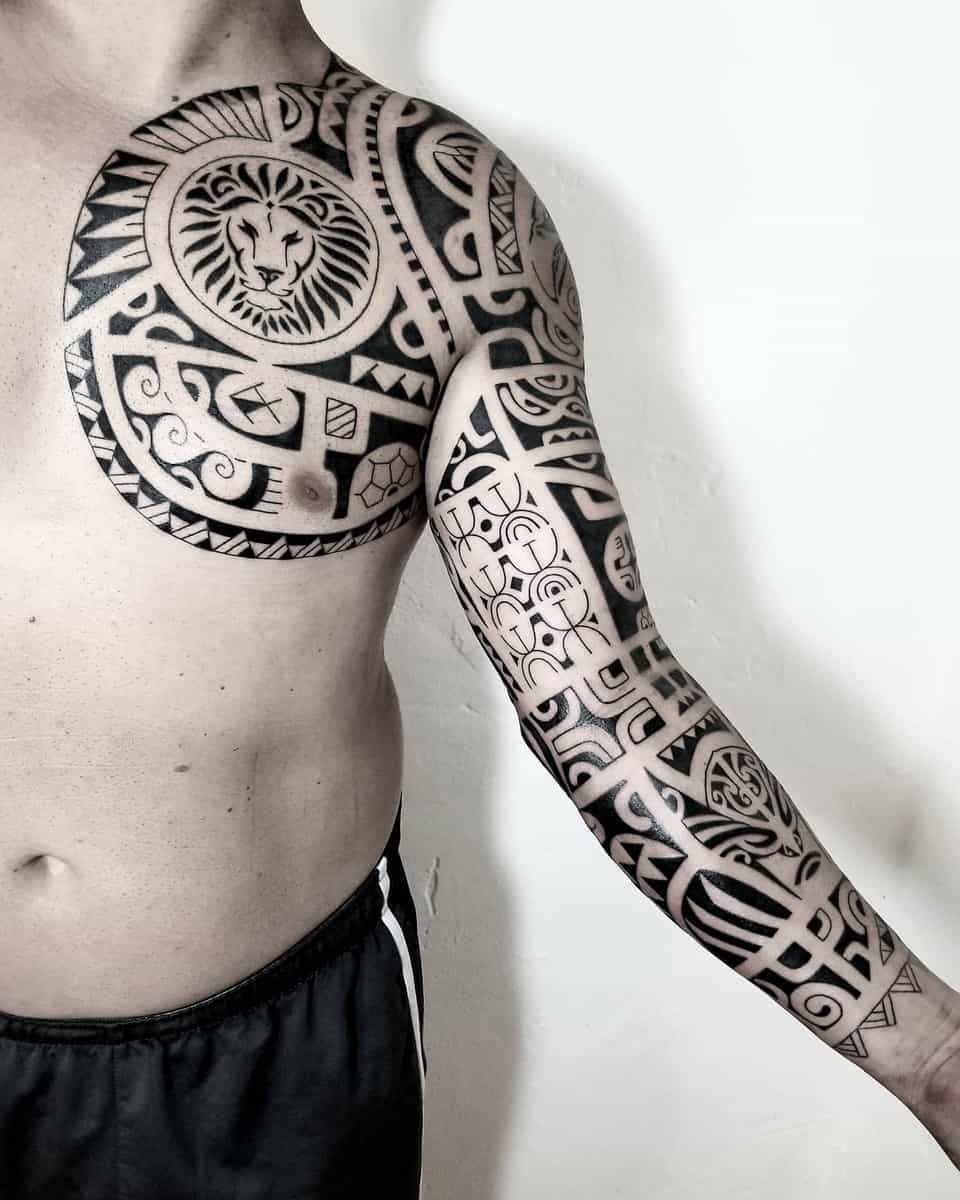 Elaborate Polynesian tribal tattoos on chest and arm, featuring a lion's head, geometric patterns, and a turtle
