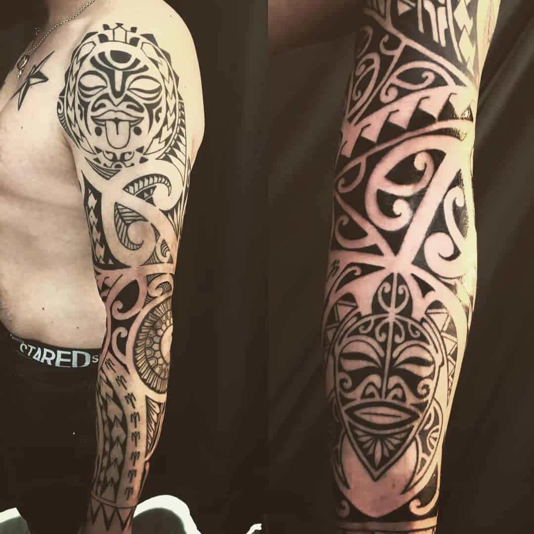 Intricate Polynesian tribal tattoos covering the upper arm and forearm in black ink