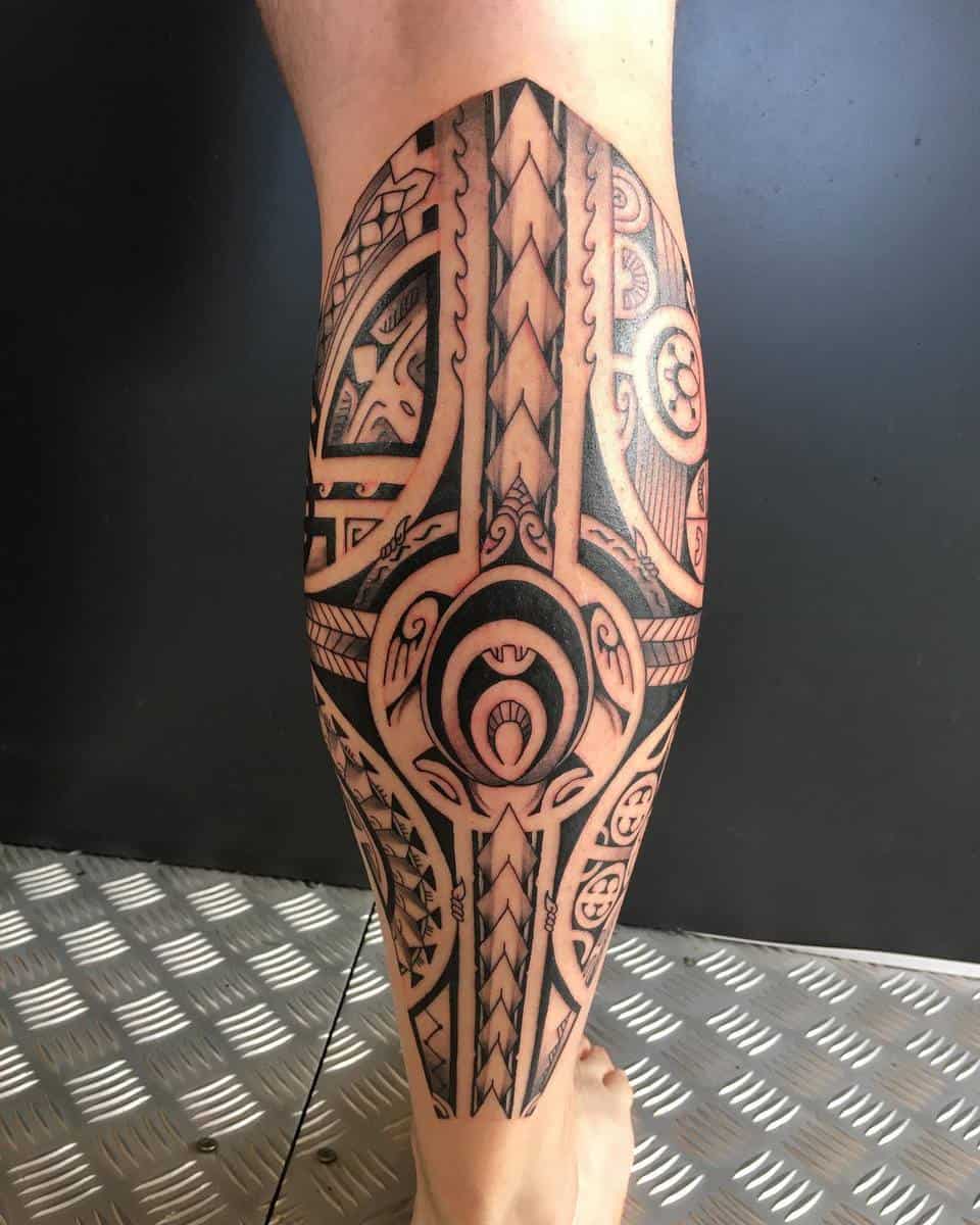 Calf with intricately designed tribal tattoo featuring geometric and curved patterns in black ink