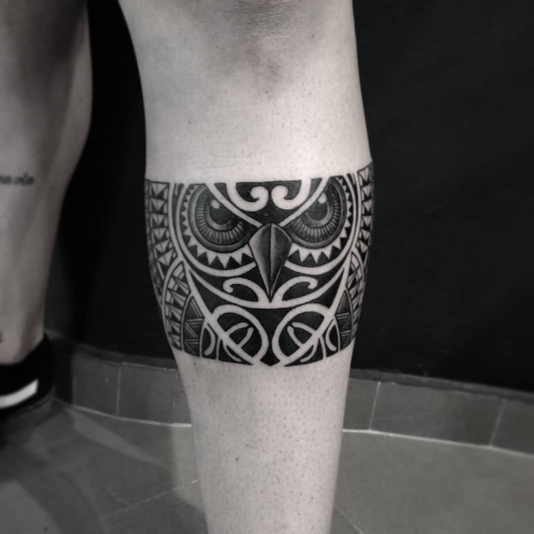 Black and white tattoo of an owl with intricate geometric patterns on the back of a calf