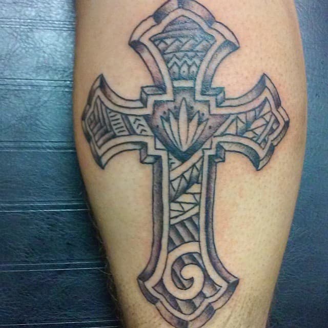 A tattoo of a cross adorned with intricate tribal patterns graces the skin, weaving together geometric and curved designs in perfect harmony