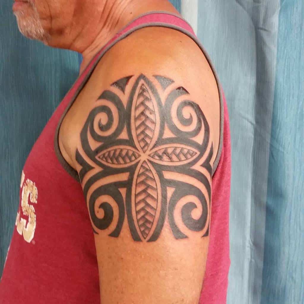 A man with a tribal tattoo and a small cross inked on his upper arm