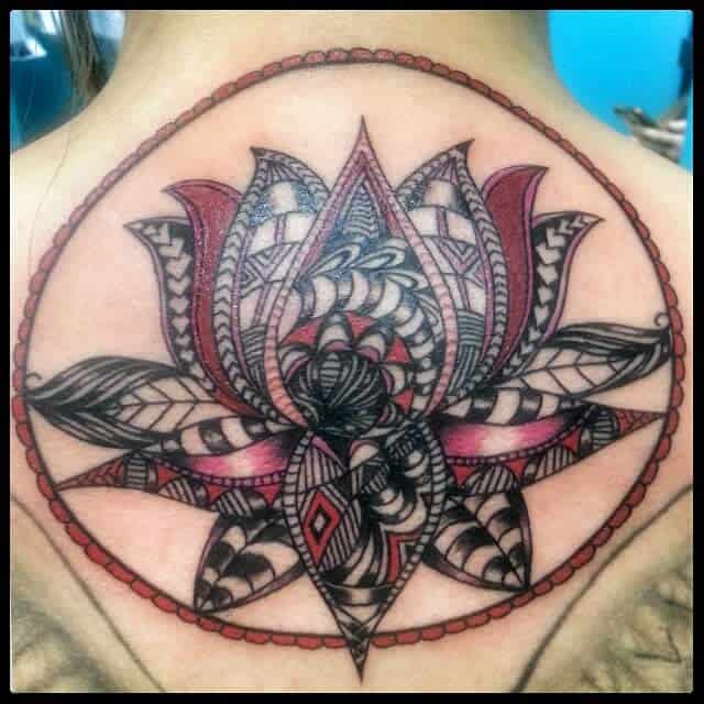 Polynesian-inspired lotus flower tattoo with intricate black and red patterns, encased in a circular frame on the upper back
