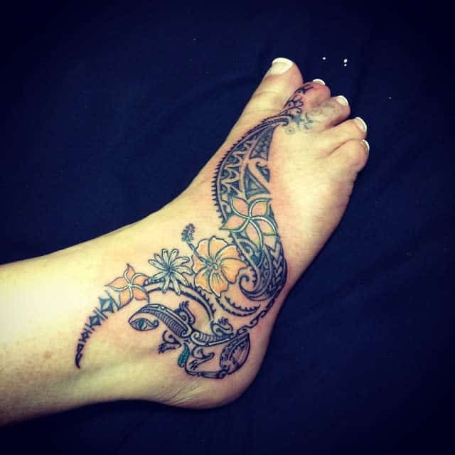 Elegant Polynesian-inspired foot tattoo featuring detailed tribal patterns and vibrant floral accents for a graceful look