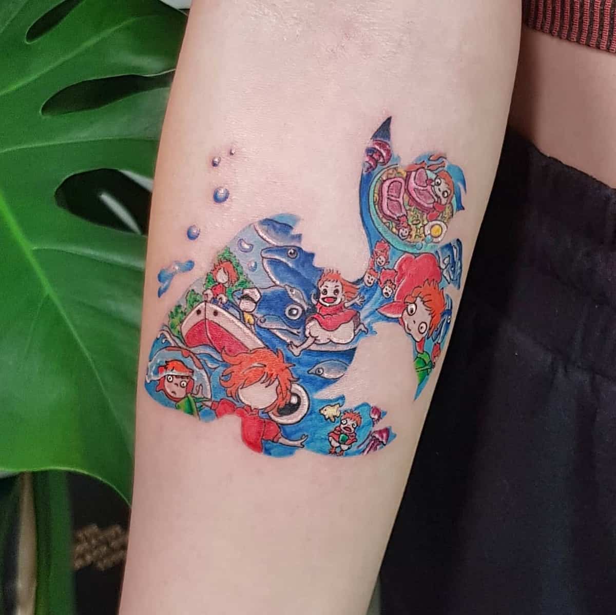 Intricate tattoo featuring various scenes from Studio Ghibli's Ponyo shaped like a fish on the forearm