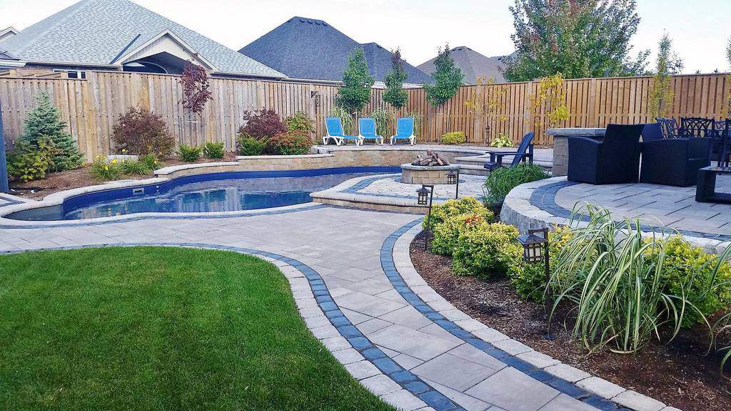 large backyard with stone paver deck and pool