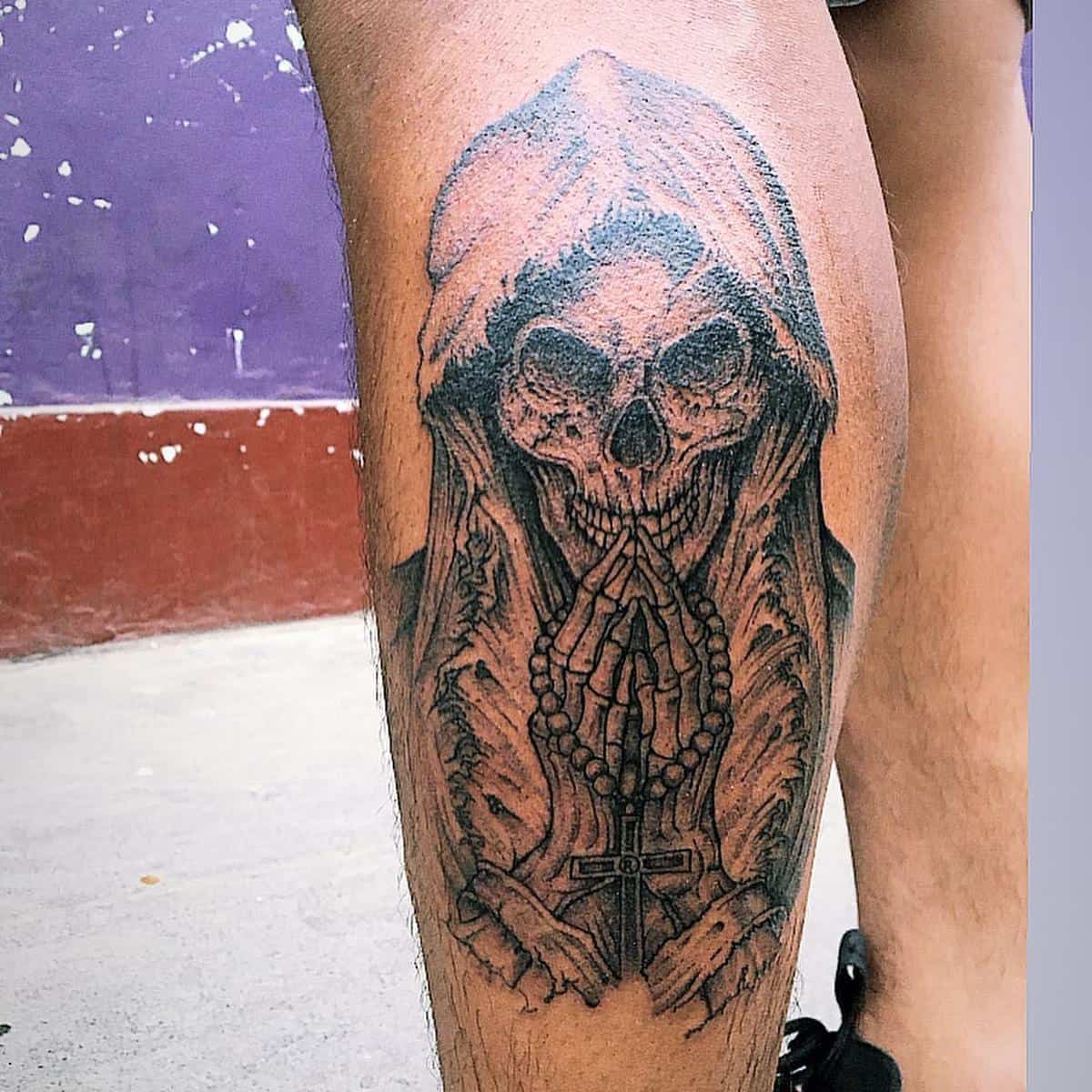 A detailed black ink Santa Muerte tattoo featuring a praying skeleton with rosary and hooded cloak