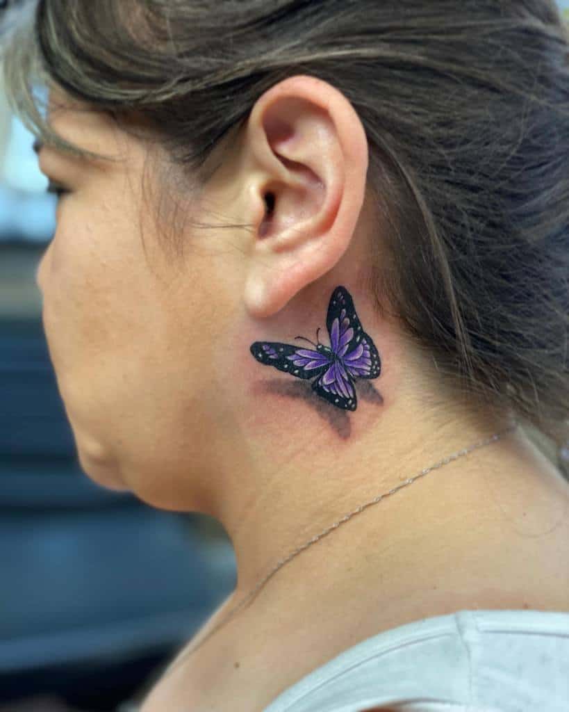 Woman's neck with a colorful butterfly tattoo behind her ear