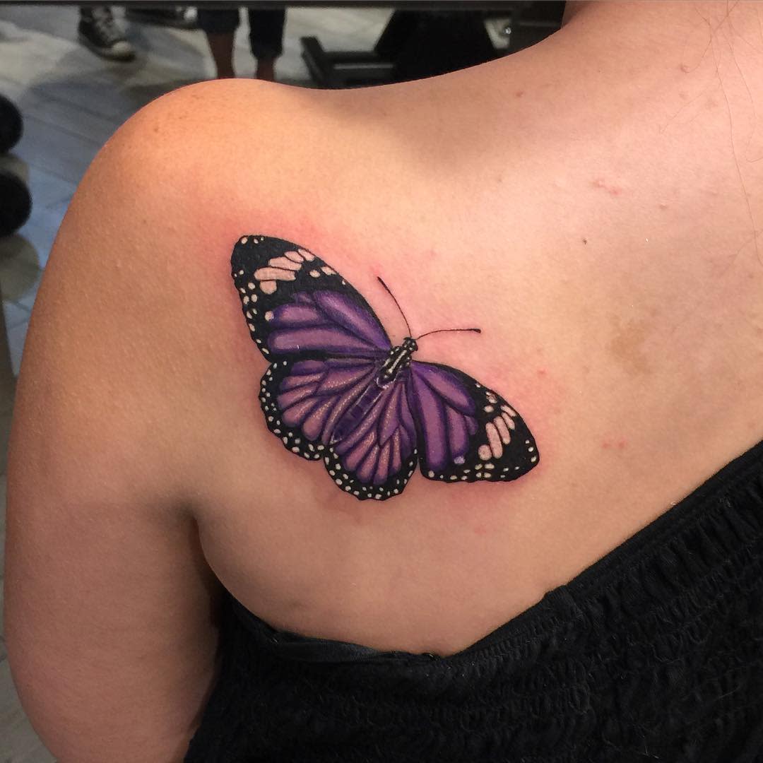 Purple and black butterfly tattoo on a left shoulder