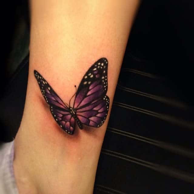 Purple butterfly tattoo on a lower leg above the ankle
