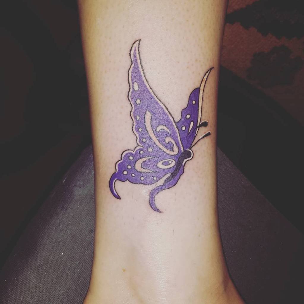 Tattoo of a purple butterfly with white spots on an ankle