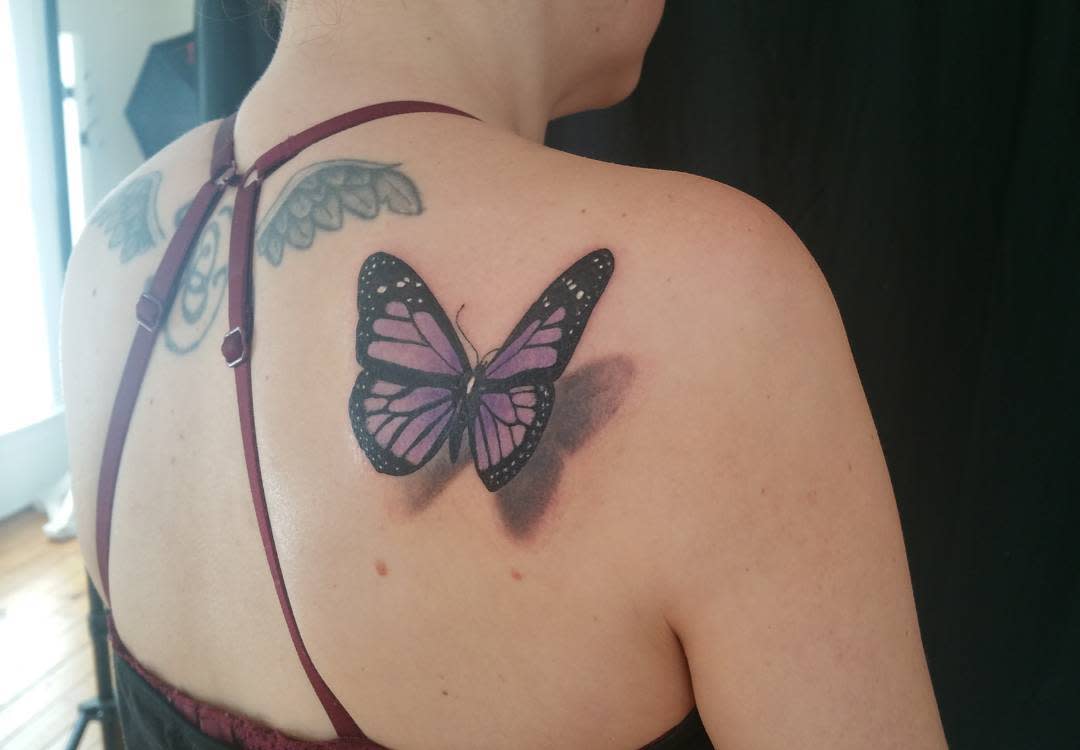 Tattoo of a purple butterfly on a woman's back