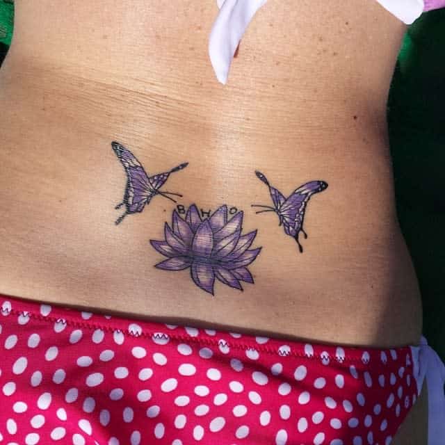 Lower back tattoo of two purple butterflies and a lotus flower