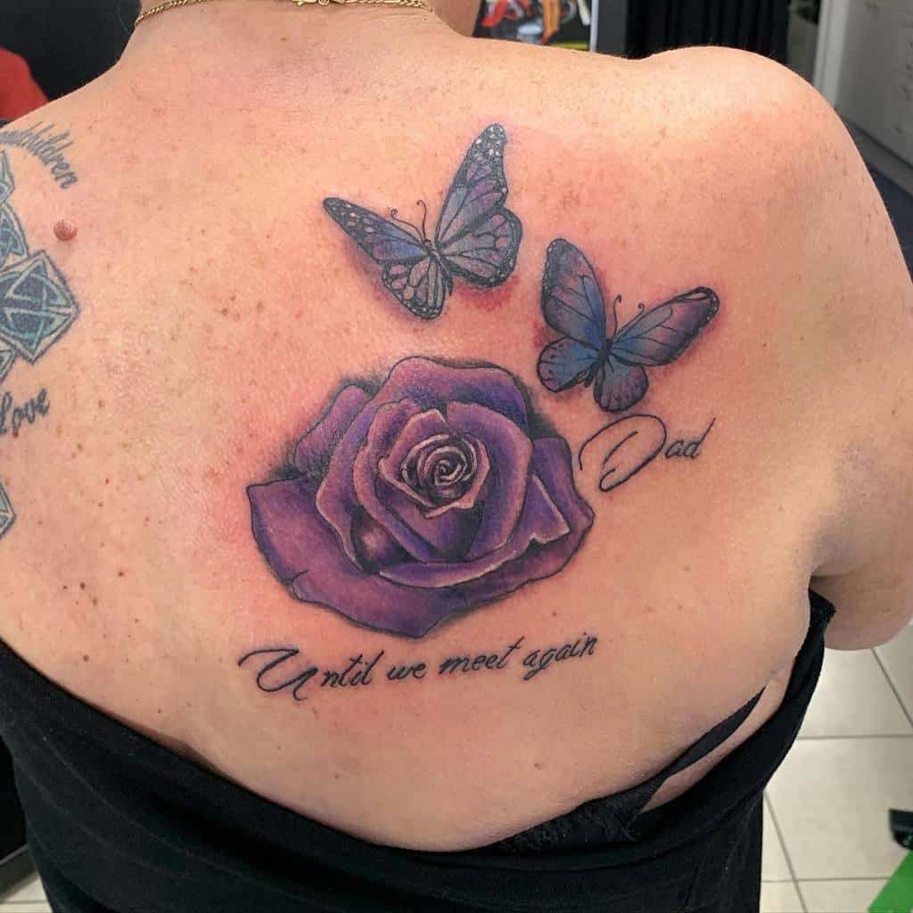 Back tattoo of a purple rose with two butterflies, and the words "Until we meet again" and "Dad"