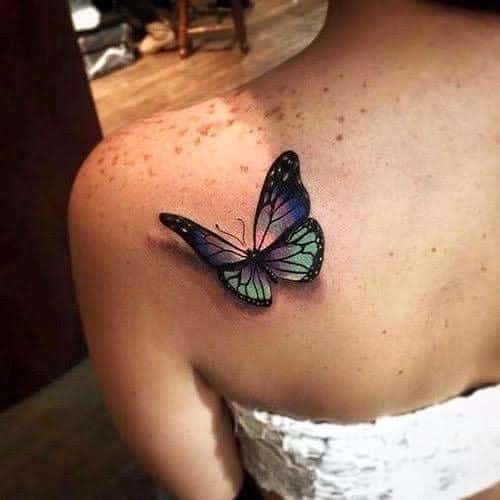 Realistic 3D butterfly tattoo on the upper back, featuring vibrant blue and green hues with intricate shading for a lifelike effect.
