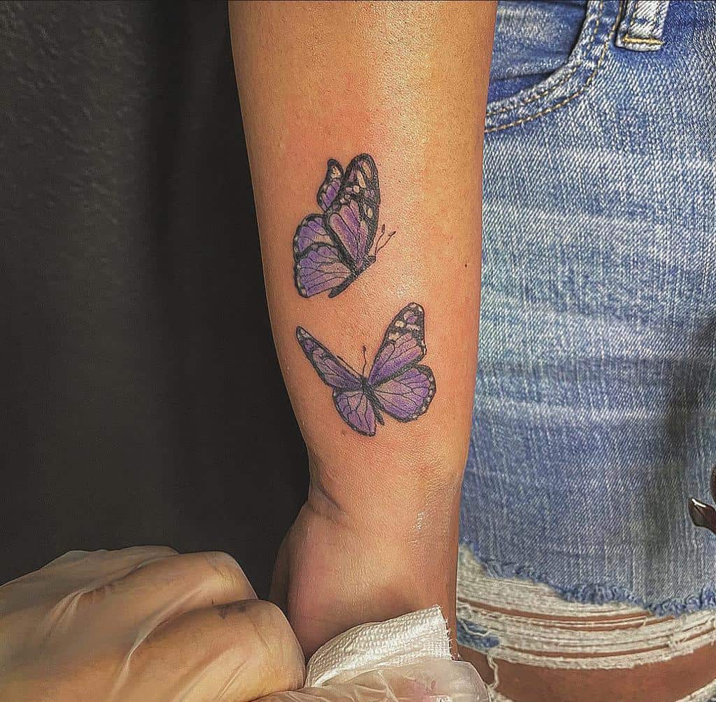 Two purple butterflies tattooed on a wrist