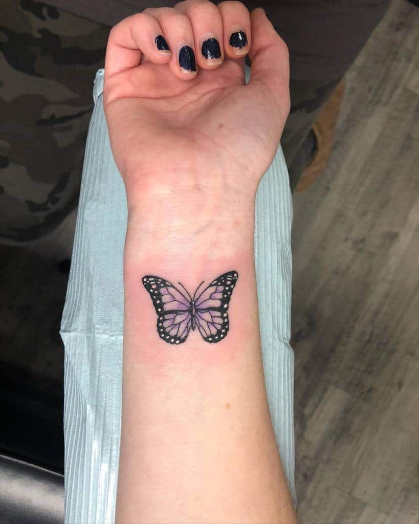 A purple and black butterfly tattoo on a wrist