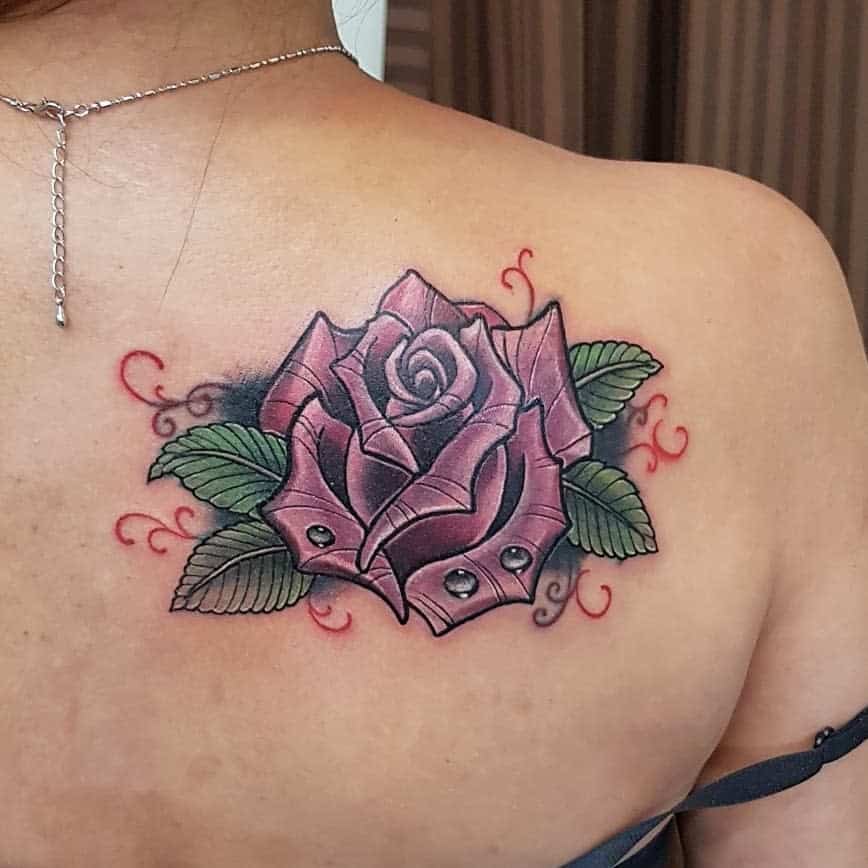 Tattoo of a purple rose with green leaves and red swirls on an upper back