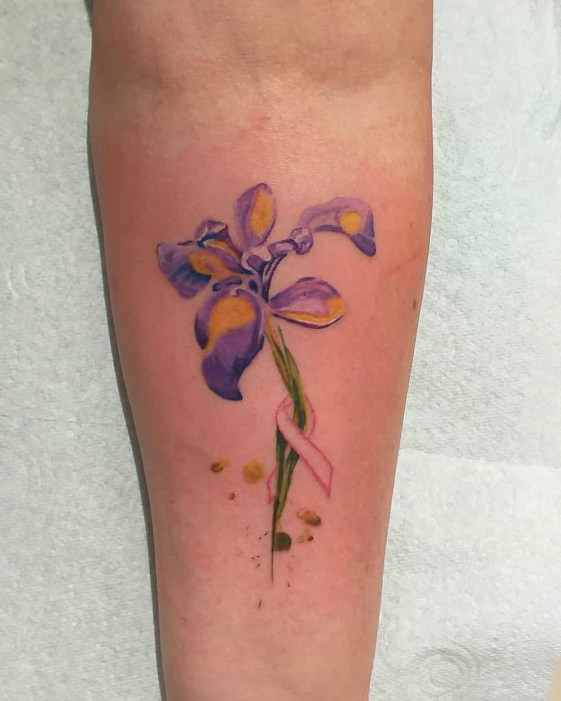 A stunning tattoo of a vivid purple iris with a delicate pink ribbon on the forearm